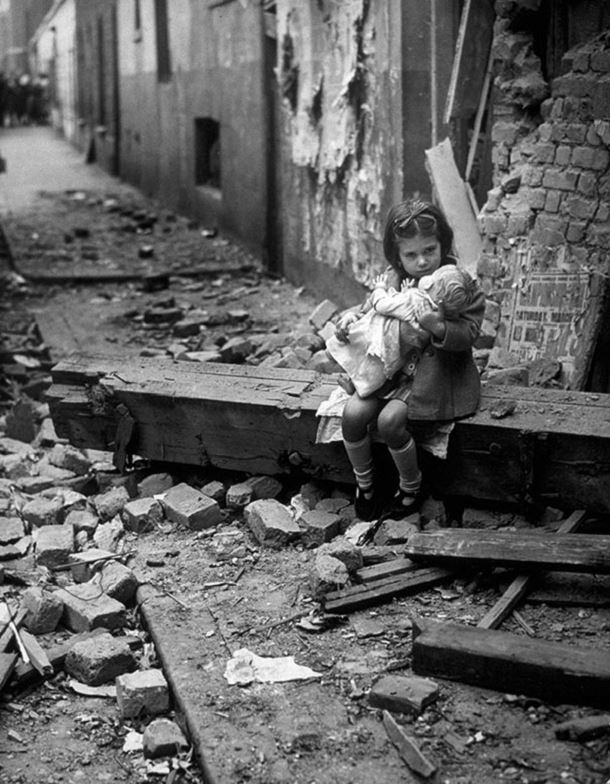 Dans les ruines de sa maison bombardée, une petite fille tient sa poupée dans les bras…  La photo a été prise en 1940